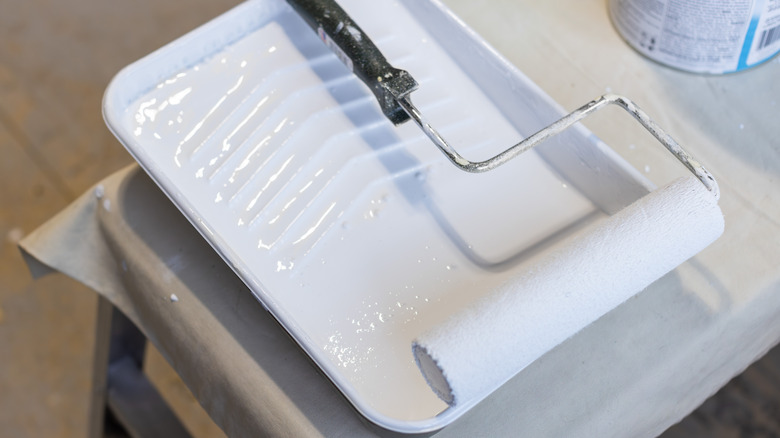 A close-up photo of a paint tray filled with primer paint and a paint roller