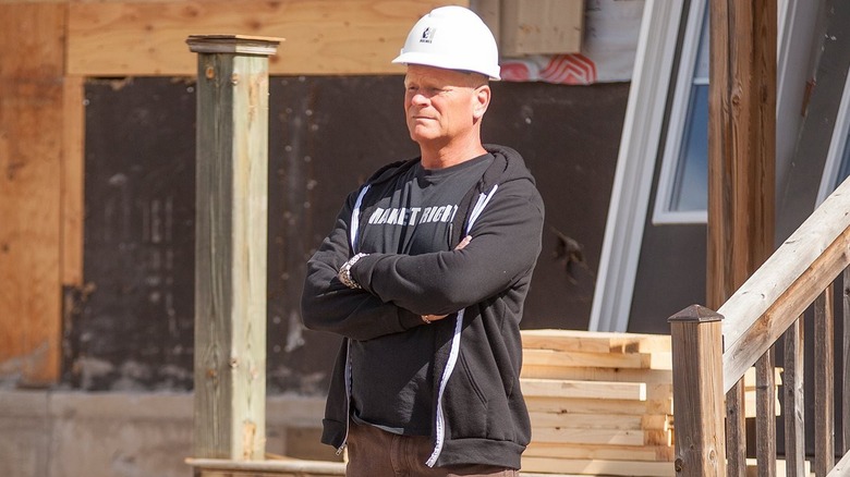 Mike Holmes in hard hat and black t-shirt and hoodie on construction site