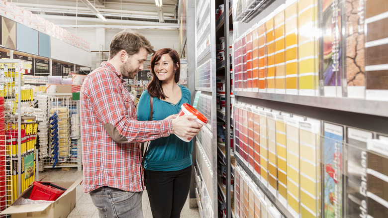 Smiling couple picking out paint in a store