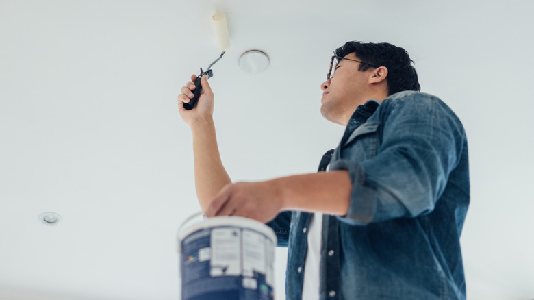 Low angle view of a young man painting the ceiling with paint roller