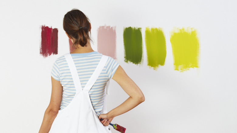 woman looking at different paint colors on a white wall