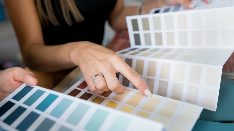 Close-up of two women choosing samples of wall paint.