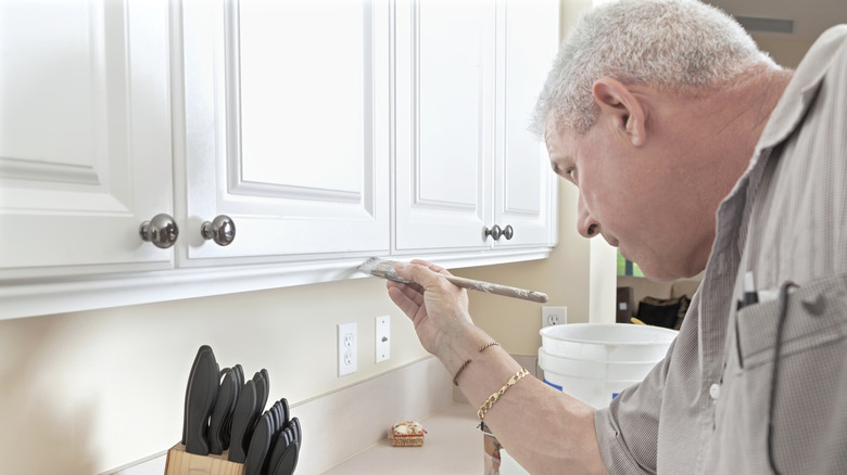 Man painting kitchen cabinets white