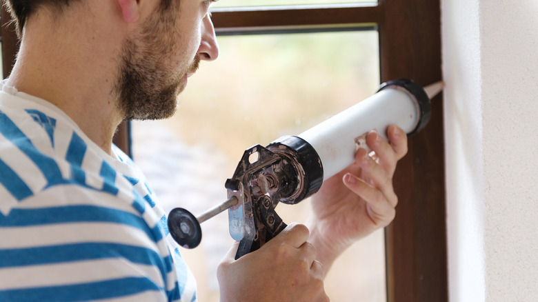 Man using caulk on window