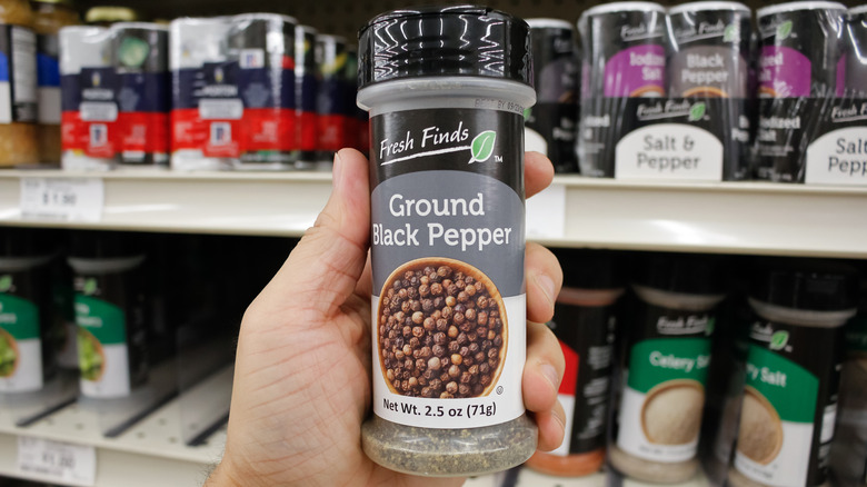 hand holding black pepper container