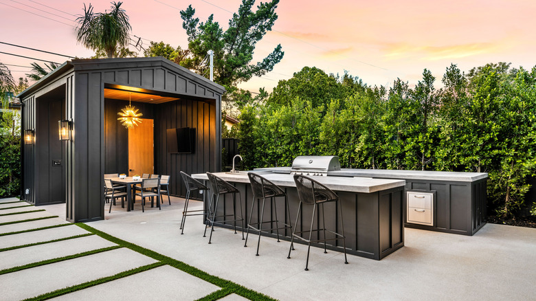 A rustic outdoor kitchen and dining area designed with natural stone and black color accents.