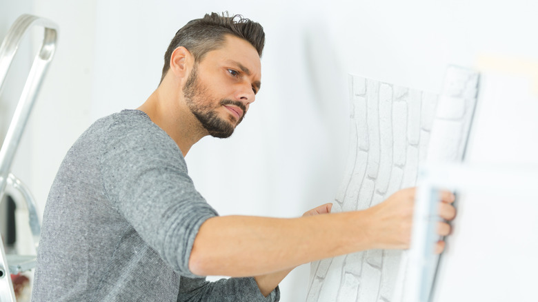 man putting up wallpaper