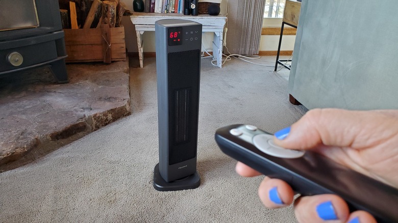 brown-haired woman sitting on couch using remote control for Pelonis heater