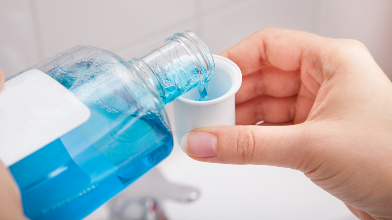 hand pouring mouthwash into cup