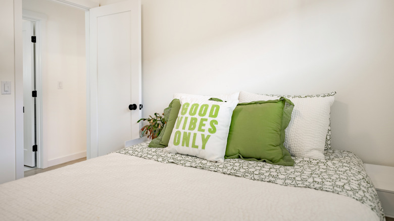 Queen side bed in a bedroom with white and green pillows