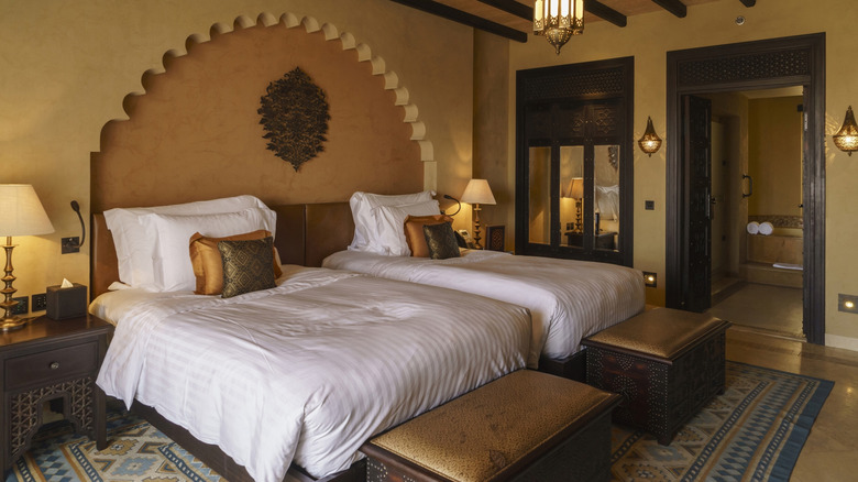 two beds side by side in hotel room with pillows arranged on them