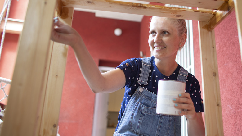 Woman painting wood shelf