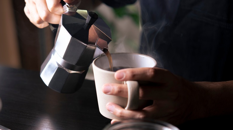 hand pouring coffee into mug