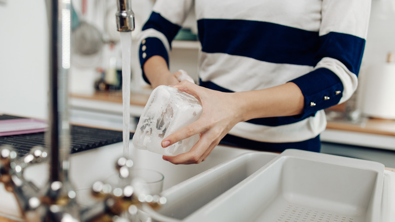 Woman washes container in sink