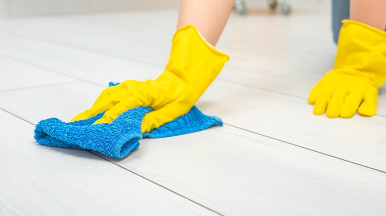 gloved hand cleaning tile floor