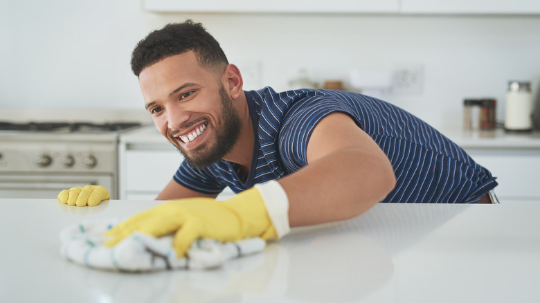 man wiping down kitchen counter