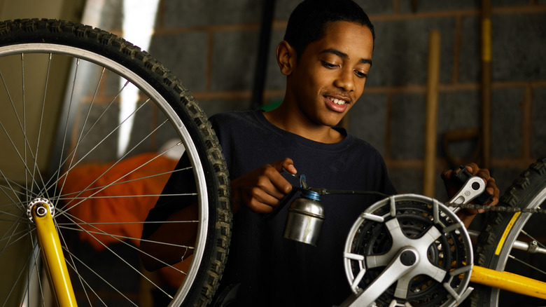 Boy oiling a bike chain