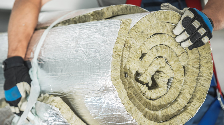 person holding roll of mineral wool 