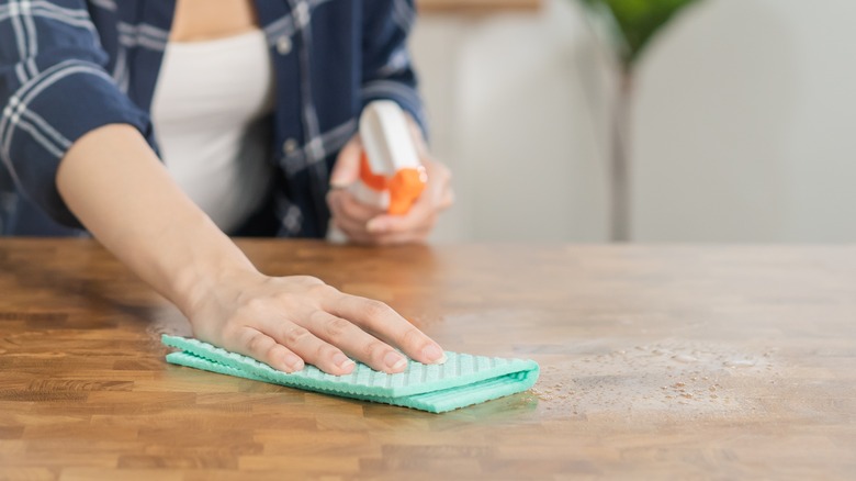 Hands spraying and wiping table