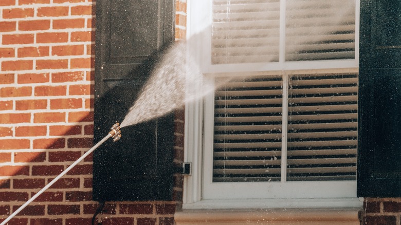 Person power washing window