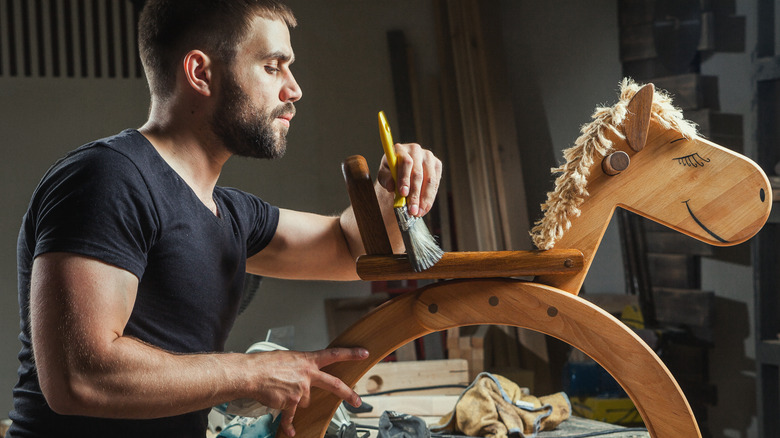 Applying varnish to child's toy