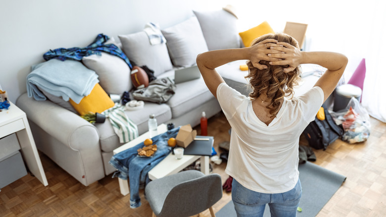 woman standing in a cluttered room