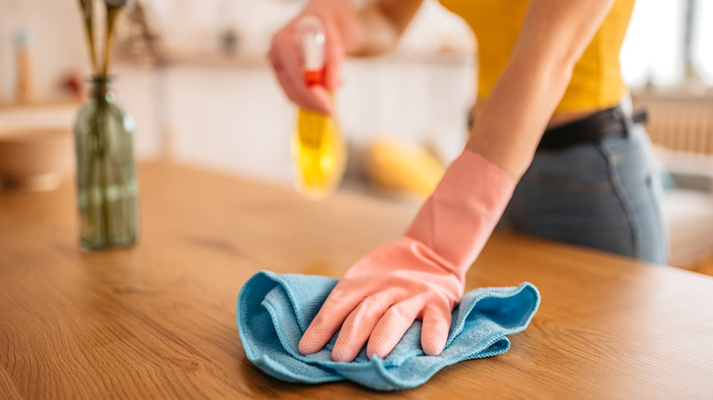 Woman dusting counter with spray