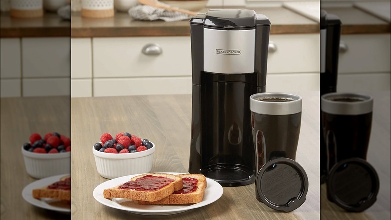 Black + Decker single serve coffee maker next to toast with jam and a bowl of fruit.