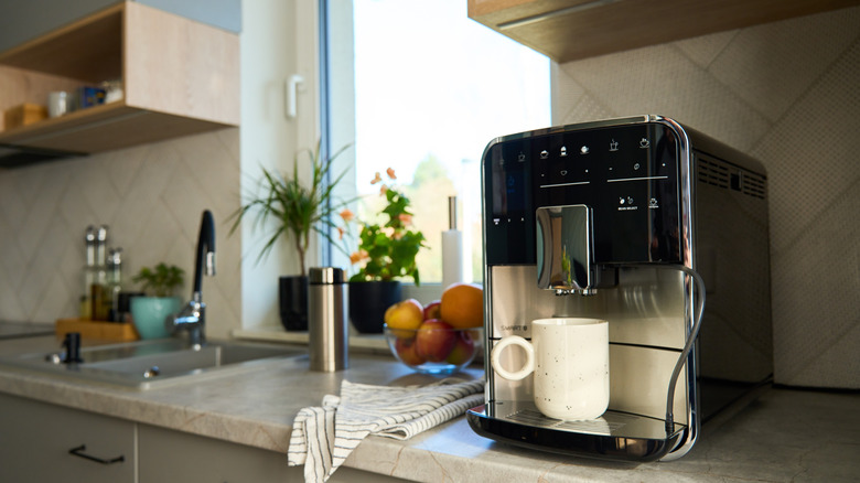 Coffee maker brewing a cup of coffee on a kitchen counter next to the sink.