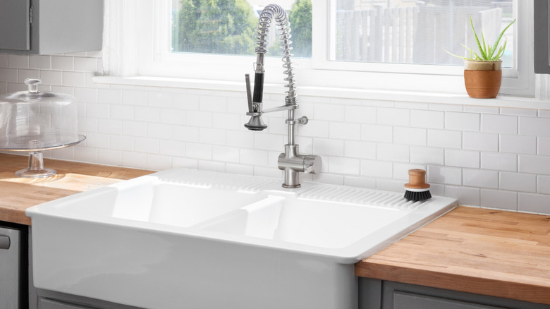 A kitchen sink detail with a butcher block wood countertop,