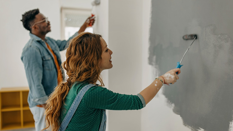 couple painting wall gray