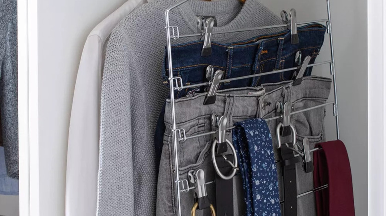 pants and belts hanging from a tiered hanger in closet