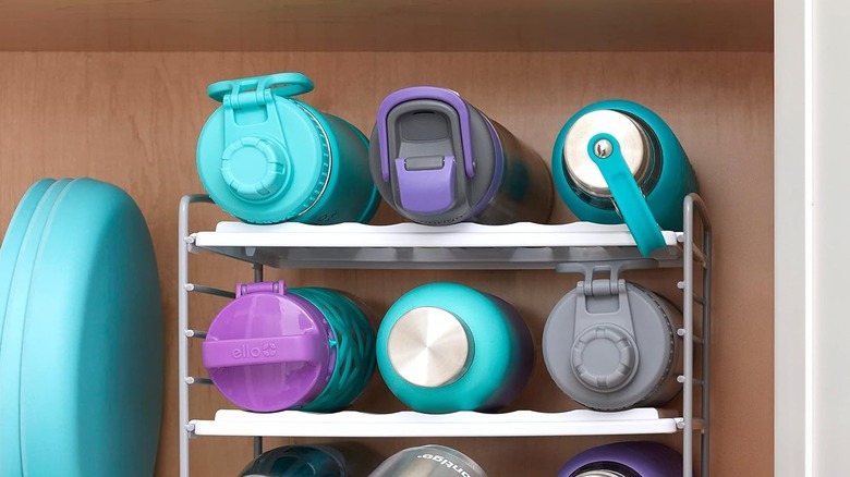 stacked multi-colored water bottles on a white rack in cabinet