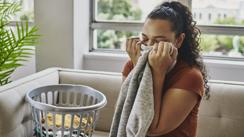 Woman sniffs laundry fresh from the dryer