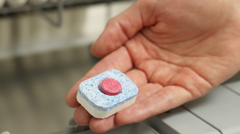 Hand holding dishwasher detergent tablets