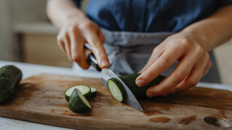 person slicing cucumber