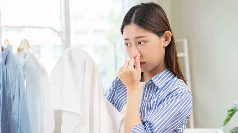 Woman holding her nose over laundry