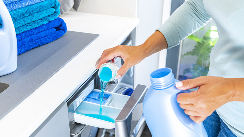 Woman adding fabric softener to washer