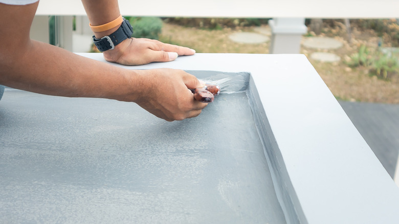 person painting concrete for porch or deck