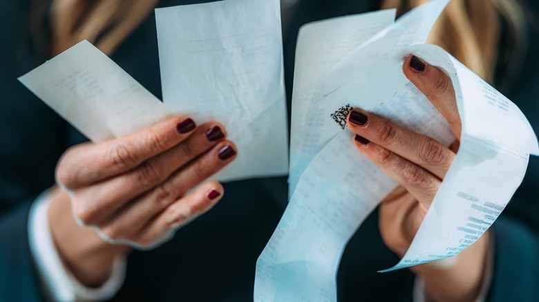 woman comparing receipts in hands