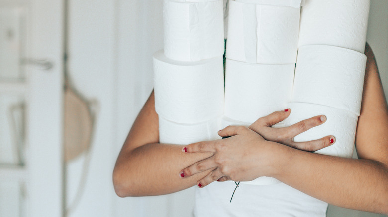 person holding toilet paper rolls