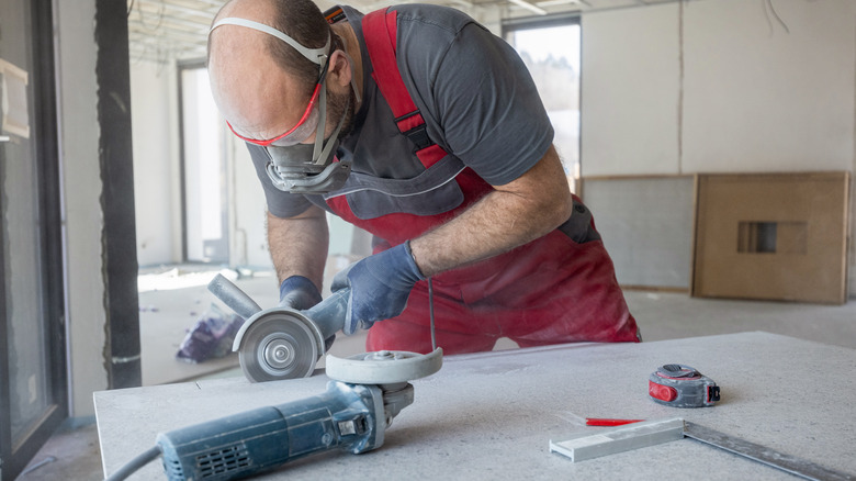 Man using angle grinder to cut stone