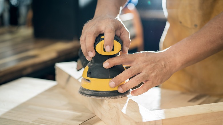 Worker using an orbital sander