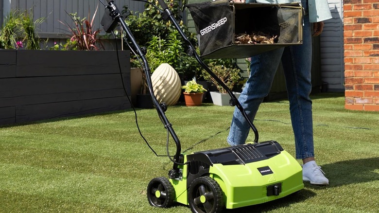 woman emptying bin on turf sweeper