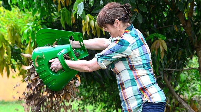 woman picking up leaves with hand rakes