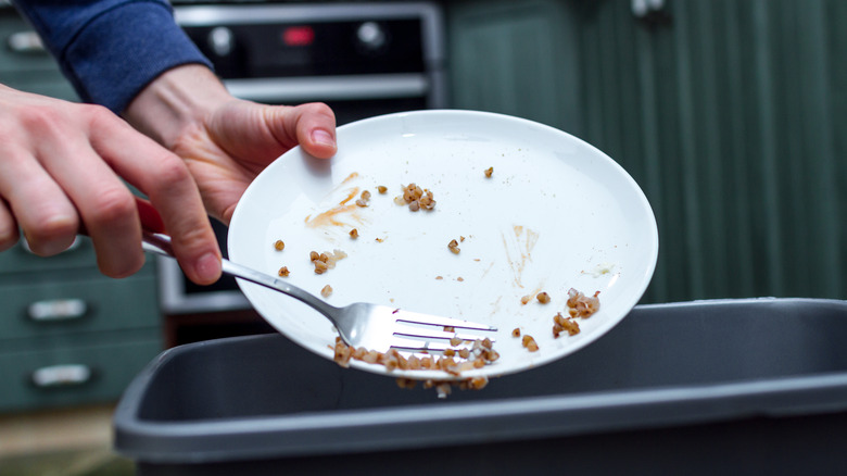 Person scraping food into trash