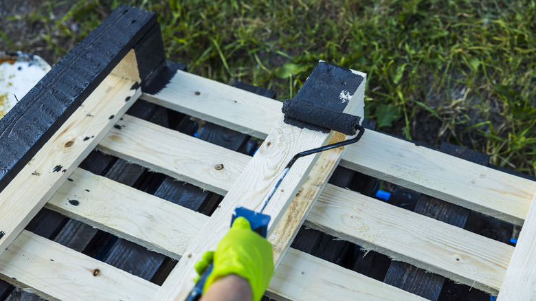 person painting pallet with roller