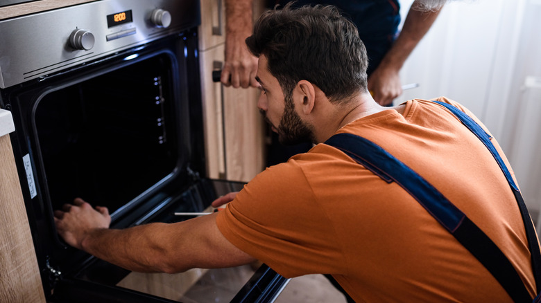 man inspecting oven