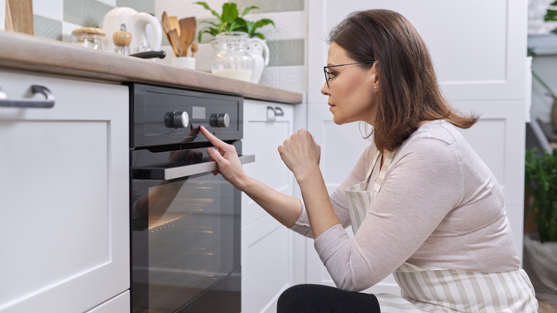 woman pressing button on oven