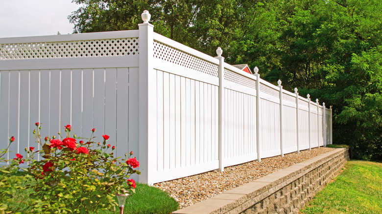 A white vinyl fence in a sunny garden location